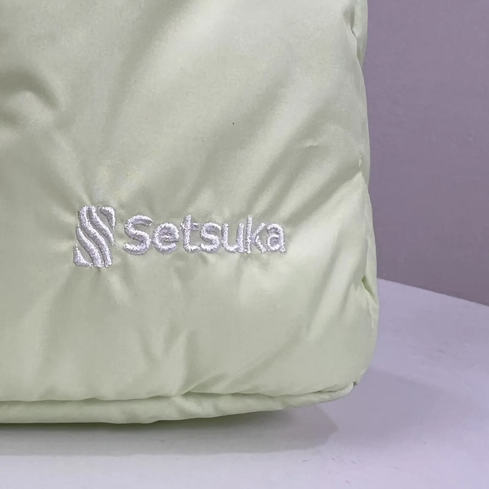 Logo Setsuka thêu chỉ trắng trên túi chần bông xanh bơ, chụp tại xưởng
